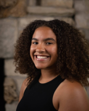 Image of Reaia Turner-Leatherman She is smilingand wearing a black shirt which shows her shoulder