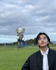 Wenrong standing in front of a large inflatable character in a grassy landscape